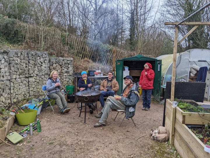 This is a photo of our volunteers sat around a fire pit drinking tea.